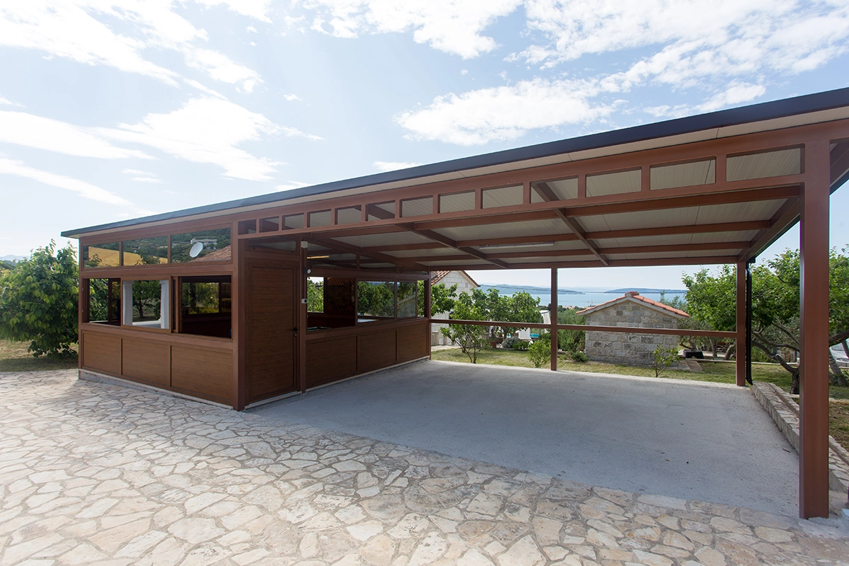Outdoor wooden structure, half of which consists of two covered parking spaces, and the other half is an enclosed playroom.